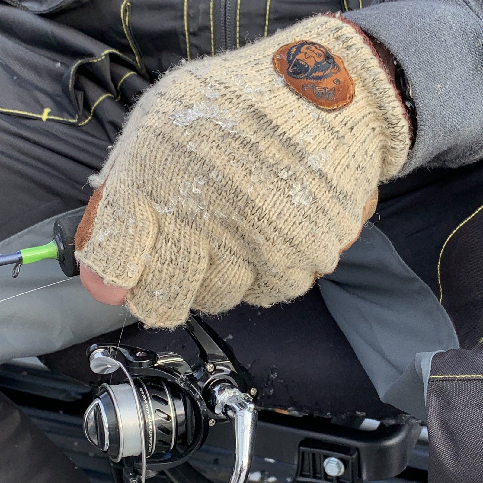 Fish Monkey Wooly ullhandske på hand som håller spö och haspelrulle i kyla